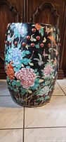Single barrel-shaped porcelain floral stand with detailed colorful flowers and butterflies on black background, red raised circular accent dots near top.