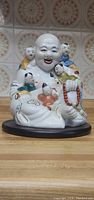 Porcelain Buddha sculpture with five children and wooden stand, front view