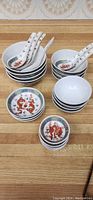 Photo of the chinaware set showing bowls stacked in piles, accompanied by spoons and plates all decorated with red dragons and blue borders.