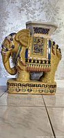 Side view of handmade porcelain elephant stand showing ornate painted details and decorative base