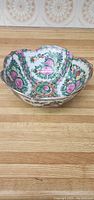 Floral porcelain bowl with pink and green flower patterns on a wooden surface.
