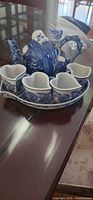 Photo of porcelain longevity teapot set with four cups and a tray, showing blue and white detailed decoration and overall condition.