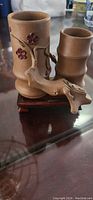 Photo of the small brown stone sculpture with two pots on a wooden stand showing floral and bamboo design details.