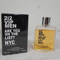 Photo showing 2i2 VIP Men Eau de Parfum bottle with amber liquid alongside its black sealed box with white text, showing 100ml volume.
