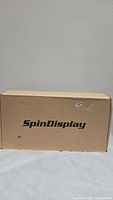 Closed cardboard box with SpinDisplay branding indicating the package for the hologram device.