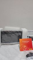 Car MP5 player in new condition with protective foam and plastic wrap, user manual included.