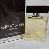 Clear rectangular glass perfume bottle with light amber liquid and brown rectangular cap alongside original dark brown box labeled 'GREAT MAN POUR HOMME Eau de Parfum 100ml 3.4 fl. oz.'