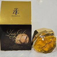 Photo of Lady Gold perfume bottle next to its gold and black box by ZTG Fragrances.