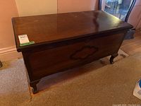 Closed cedar lined wooden blanket box showing the polished dark wood grain and carved design on the front panel.