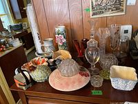Full view of assorted glass and pottery items on table showing various vases, candy dishes, flower frogs, and bowls