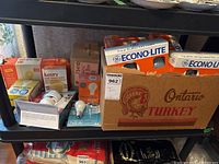 Shelf with multiple boxes and loose household light bulbs including GE Best Buy and Econo-Lite brands