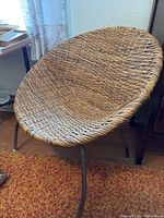 Chair viewed from an angle showing rattan woven seat and metal legs
