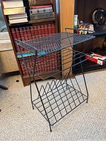 Side angle view of vintage metal record rack showing angled slots and top perforated shelf