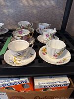 Overview photo of six bone china teacups and saucers with floral and wheat designs, various English makers.