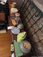 Overview of six trinket boxes on wooden bench: metal music box, ceramic figurine box, plastic etched box, painted metal box, wooden accordion box and small wooden box