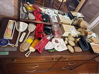 Overview of vanity set contents including brushes, mirrors, combs, jewelry boxes, and small frames on wooden dresser surface.