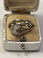 Three rings in presentation box: filigree ring, plain band, and art deco-style ring