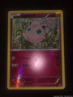 Front image of Jigglypuff reverse holo Pokémon card with visible foil reflection and forest background artwork