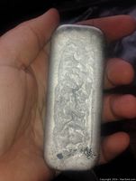 Large pewter casting bar held in hand, showing texture and size.