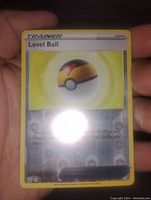 Photo of Level Ball Pokémon Trainer card showing reverse holo surface and card details. Card held in hand to indicate size and condition.
