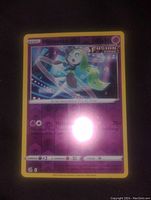 Photo showing front side of Meloetta holographic foil Pokemon card with fusion strike branding and energy symbols, some glare on card surface.