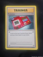 Photograph of a single Pokémon Trainer Card featuring the Pokedex item with yellow border and text details.