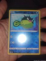 Photo of the Pokemon Quillfish holographic foil collectible card held in hand, showing detailed front including HP, attacks, and holographic foil pattern.