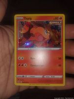 Photo showing front of Single Strike Tepig Holo Foil Pokemon card in hand, displaying card details and holo foil effect