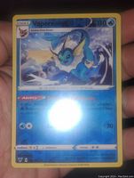 Front view of Vaporeon Pokémon card in reverse holo finish with visible water effect and holographic shine.