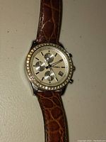 Front view of Fossil ES-1651 wristwatch showing beige dial with three subdials, date window, crystal-studded bezel, and brown crocodile-pattern leather strap.