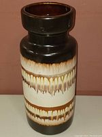 Photo of front view of medium vintage vase showing brown and cream glaze drip pattern.