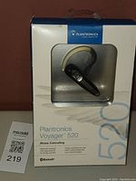 Front view of unopened Plantronics Voyager 520 box showing the Bluetooth noise cancelling headset with ear hook inside through clear window.