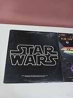 Photo showing the vinyl record album with a black cover featuring the Star Wars logo in white