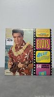 Cover of Elvis Presley Blue Hawaii RCA Victor vinyl album showing Elvis in Hawaiian shirt and lei with 14 songs.