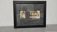 Full view of framed artwork showing two sections: a large portrait of Elizabeth Taylor with a stamp image on the left and a collection of six Elizabeth Taylor portraits on stamps on the right. Black frame with textured gray mat.