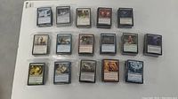 Photo showing multiple magic card stacks laid out in rows on a white surface, displaying card backs and fronts.