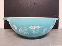 Side view of the turquoise bowl with white hot air balloon decorations around the exterior, showing details of the design.