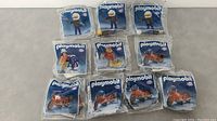 Ten sealed Playmobil ESSO figures and motorcycles in original packaging, arranged in two rows.