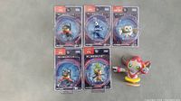 All six Pokemon toys displayed: five small figures still in MonColle-ex branded packaging and one loose figure (Magearna) with a yellow base.
