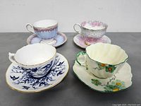 Four distinct vintage teacup and saucer sets displayed from the front showing patterns and colors.