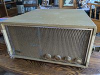 Front view of the amplifier with textured fabric covering and four control knobs on metal grille