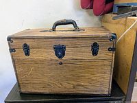 Closed antique wooden drawing cabinet showing metal locks and handle.