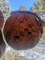 Hand-carved wood globe featuring animals and map outlines, spherical in shape with a polished wood finish and natural edges.