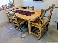 Angled front view of table and chairs showing natural edge of tabletop and log frame