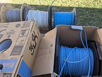 Five rolls of Cat 5e copper Ethernet cables in blue, white, and gray on spools.