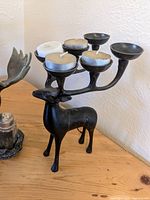 Black brass elk shaped candle holder with six candle cups for candles placed on elk's antlers.