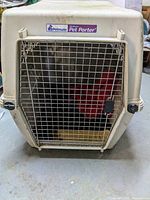 Front view of large Petmate Deluxe Pet Porter dog kennel with metal wire door and locking latch showing overall condition.