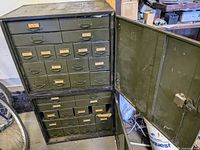 Front view of green steel parts cabinet with drawers open in upper section.