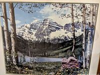 Close up image of the print depicting a small lake with mountain peaks, birch trees, and wildflowers, showing colors and details of the artwork.
