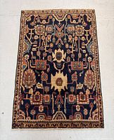 Full view of Persian Hamedan rug showing dark blue background and intricate multi-colored all over design with beige border.